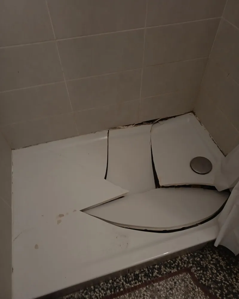 Ancien receveur de douche blanc, fendu et cassé en plusieurs morceaux